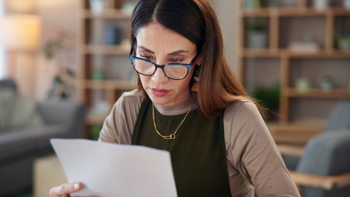 Credit Sesame vs. Credit Karma Thinking, woman and reading with paperwork in home loan payment, financial bills or bank statement. Female person, planning and glasses with document for credit card debt, invoice or investment info.