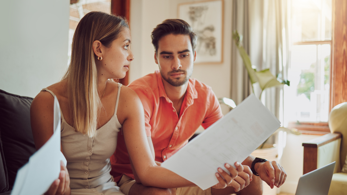 Unhappy, stressed and upset couple paying bills or debt online on with a laptop at home getting angry, planning budget. Young man and woman having a dispute over finance, savings and increasing tax Debt Consolidation Loans.