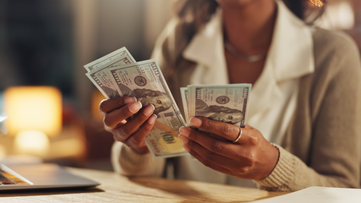 Hands, home and counting cash for budget, savings or profit from trading with laptop in night. Person, money and planning for investment, bills or payment with dollar, decision and computer in house.