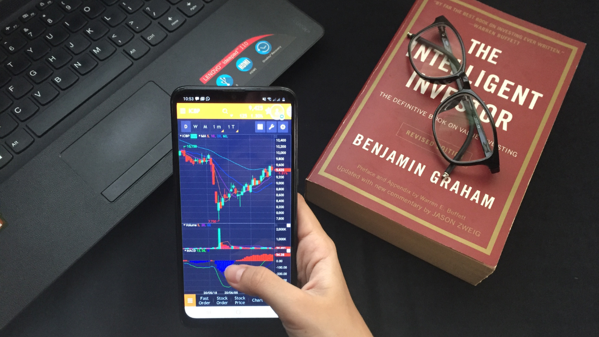 Depok, Indonesia - July 5 2020 : Making money online from home during Covid-19 pandemic by applying intelligent investor theory in stock market using mobile stock trading app.