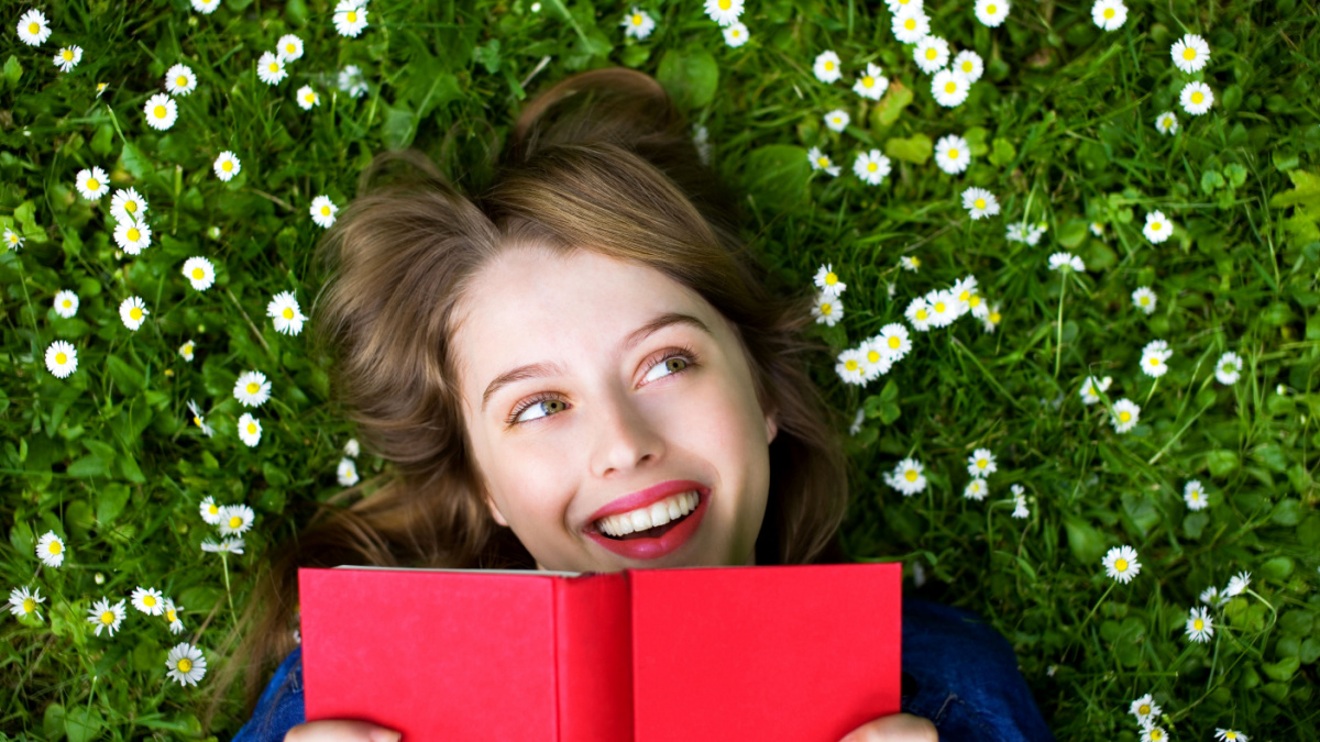 Young Girl Lying on the Grass reading book.