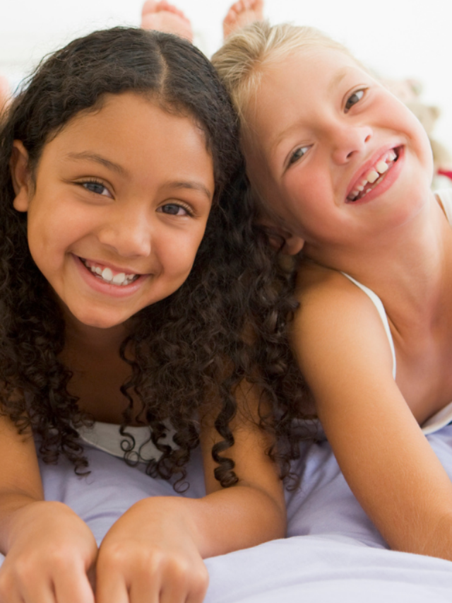 Three Young Girls Lying On A Bed In Their Pajamas