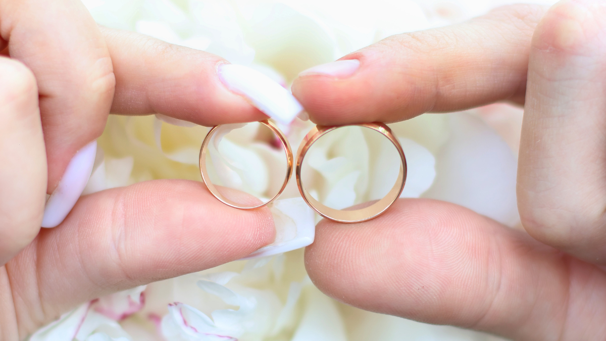 Hands of the newlyweds with wedding rings on their fingers against the background of a beautiful, white wedding bouquet. best wedding registry.