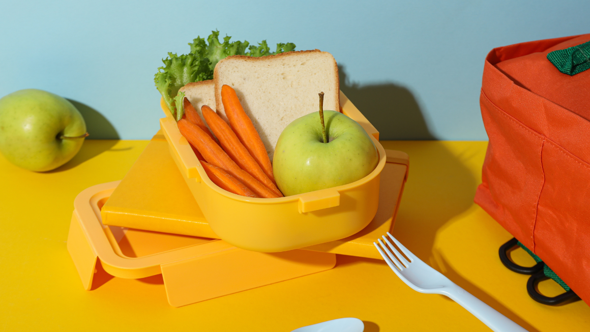 Yellow lunch box with bread, apple and carrot lunch ideas for work.