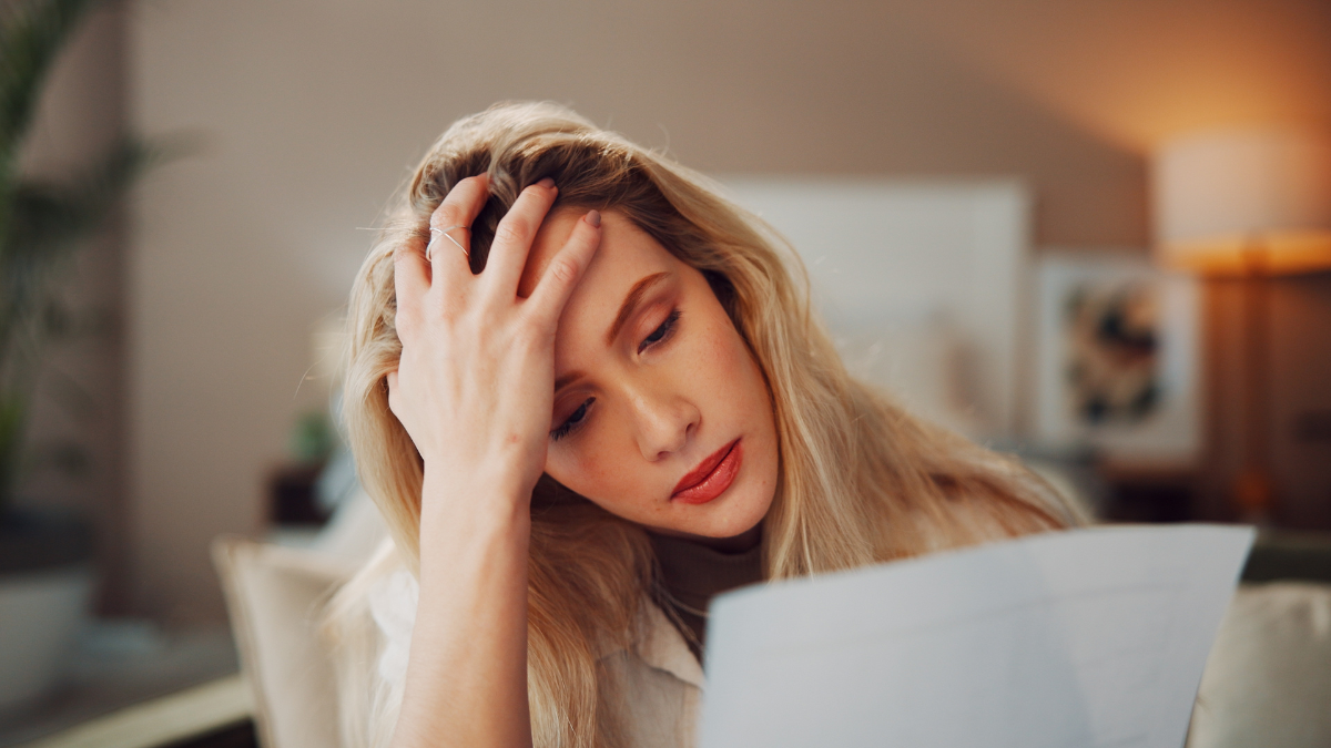 Finance, woman and stress with paperwork in home for mortgage debt, financial crisis and inflation. Headache, person or worry with statement for house expenses, missed payment or overwhelmed by bills Ways To Save Money (During a Time of Inflation).