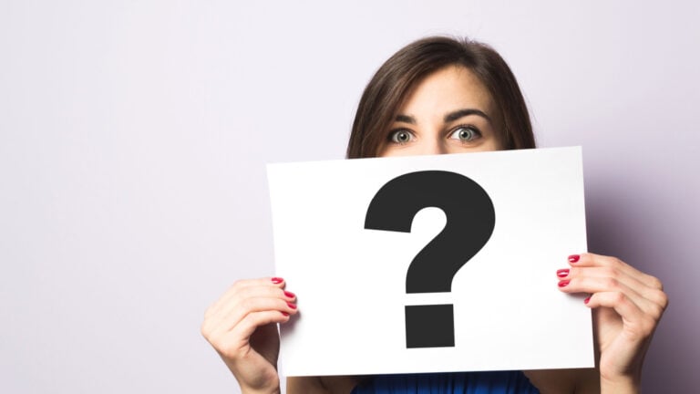 Girl holding a signboard with a question mark.