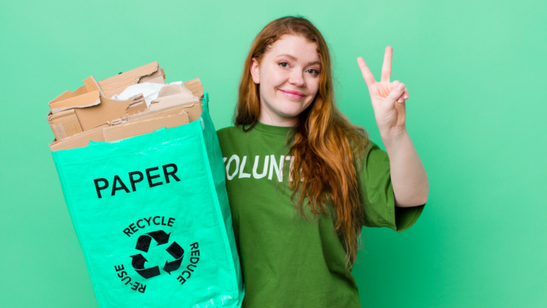 red-haired woman wearing green shirt and carrying recycling bag with paper