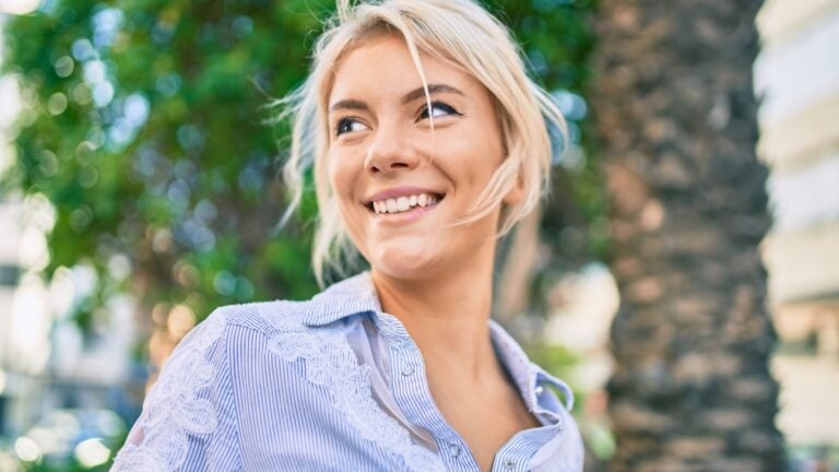 Young blonde woman smiling happy walking at the park.