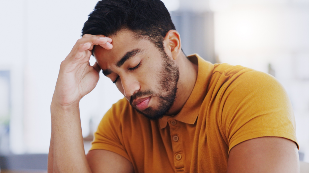 Laptop, typing and business man with headache, tired or exhausted with fatigue in workplace. Computer, migraine and depressed male professional with anxiety, burnout or sick, brain fog or stress.