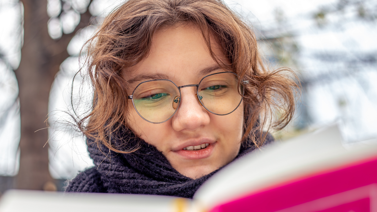 Girl reading a book on the street close-up. Teenage girl reading a book get paid to read.