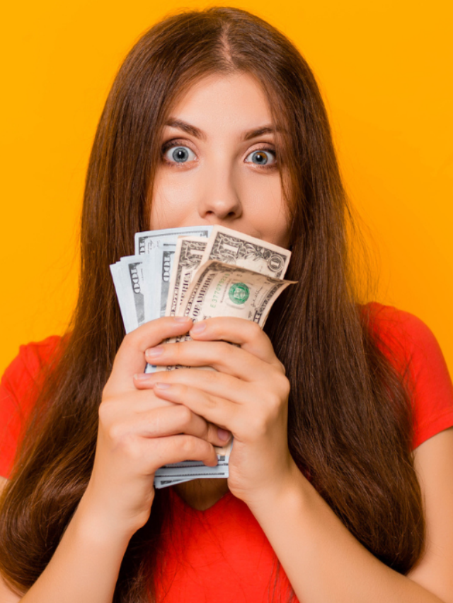 Portrait of a smiling young woman holding a bunch of money banknotes