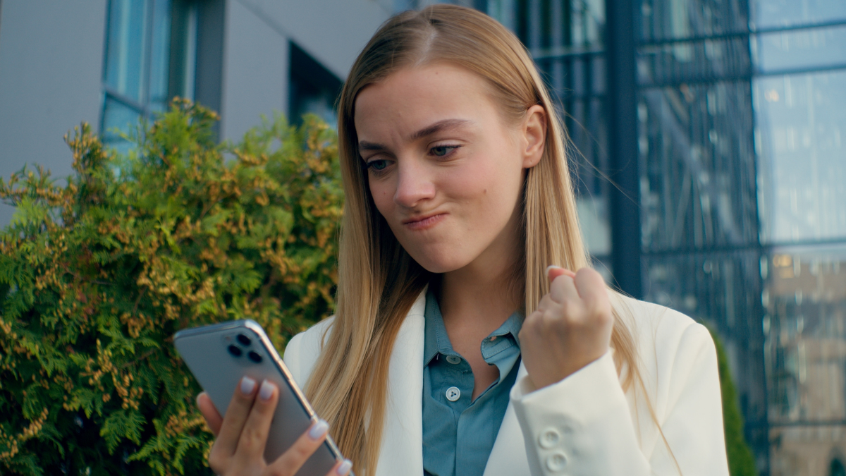 Angry Caucasian business woman reading bad message smartphone outside city frustrated female businesswoman girl irritated upset shocked sms mobile phone scam failure showing fist loss problem stress Financially Reprehensible Behaviors,
