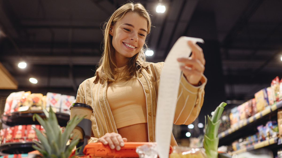 Young happy customer woman wears casual clothes read check bill shopping at supermaket store grocery shop buying with trolley cart choose products in hypermarket. Purchasing food gastronomy concept Grocery Shopping on a Budget.