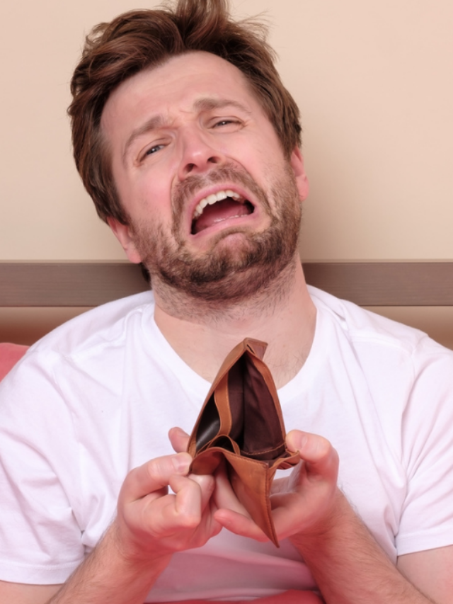 Stressed man being confused about his empty wallet sitting at bed