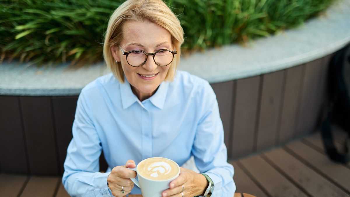 Portrait of a middle aged mature businesswoman woman drinking a cappuccino in a coffee shop anti-frugal habits.