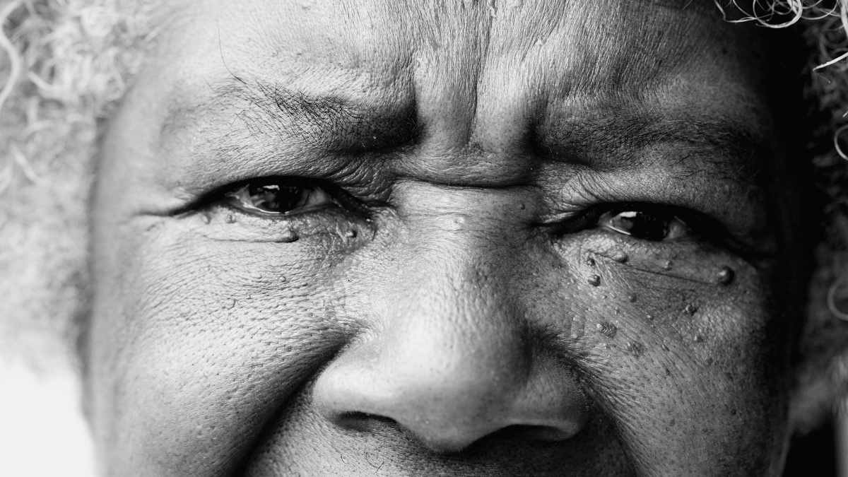 One serious senior black woman staring at camera with solemn expression in monochromatic, black and white. Macro closeup of African American person eyes and face frugal living tips from The Great Depression.