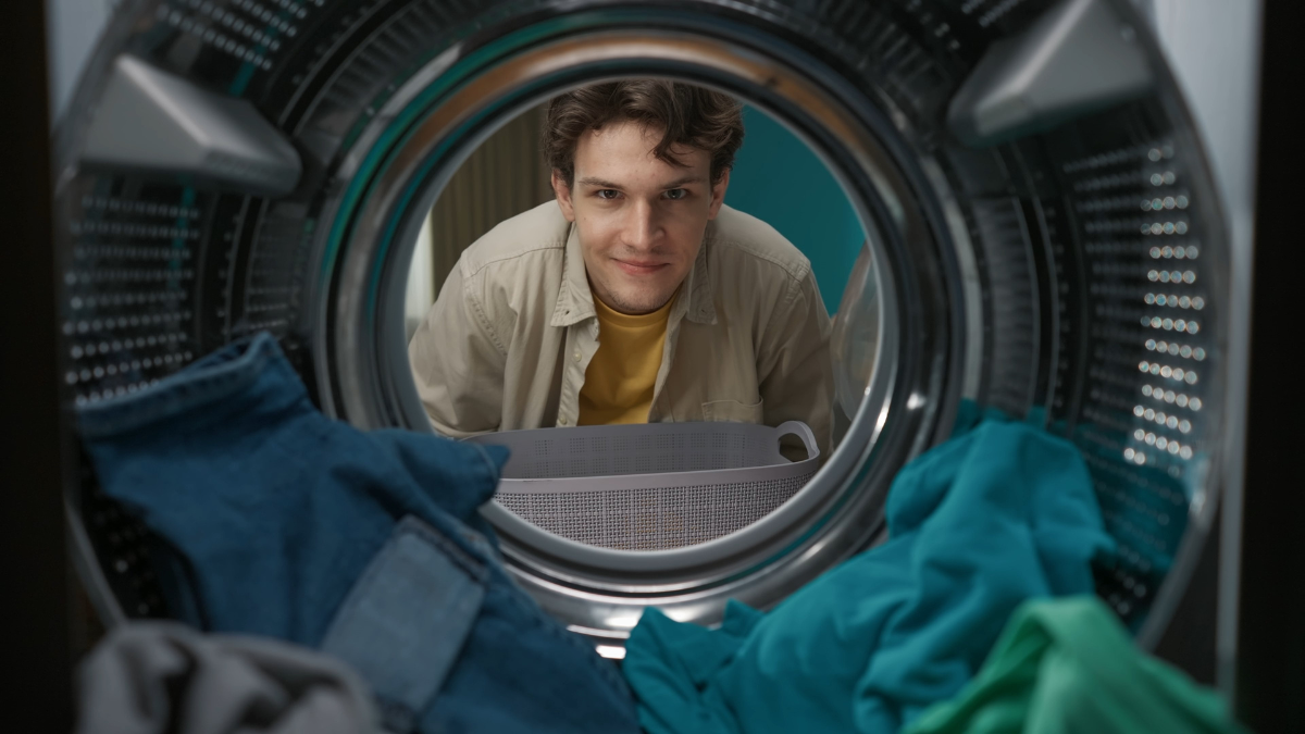 View from inside the washing machine, adult man looking at the camera and smiling. laundry mistakes.