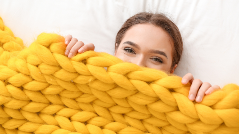 woman laying under knitted blanket