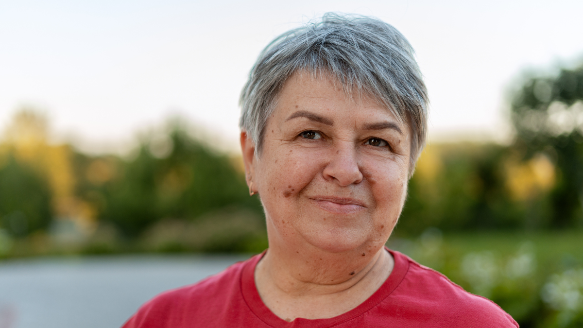 Portrait of confident mature woman with gray hair and red t shirt, enjoying a sunny day at park How Does a 401(K) Work?