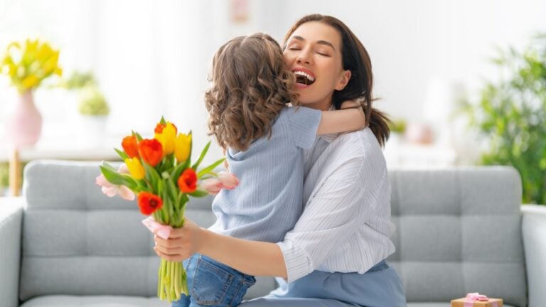 Happy mother's day. Child daughter congratulates mom and gives her flowers. Mum and girl smiling and hugging. Family holiday and togetherness.