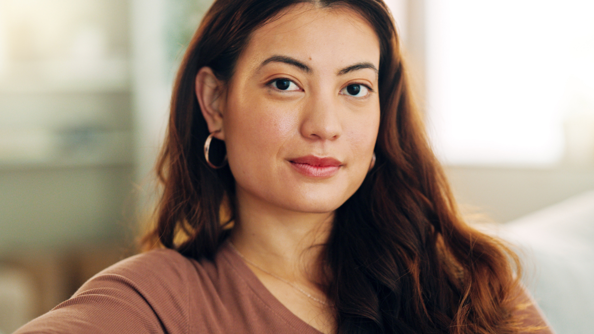 Serious woman, relax and home with a beautiful asian female feeling calm, peaceful and enjoying her free time on the sofa at home. Portrait and face of a young female sitting in her singapore house frugal mindset.