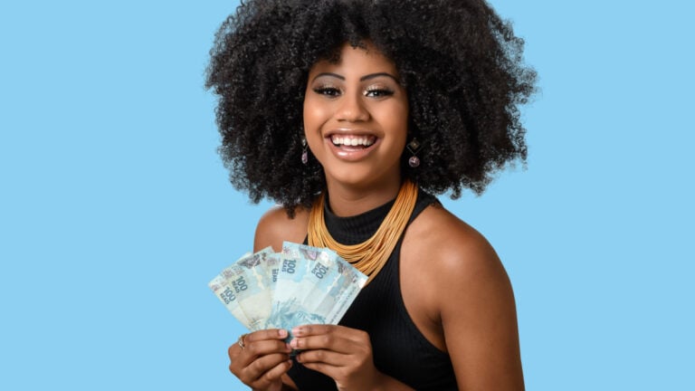 young black woman smiling holding brazilian money bills.