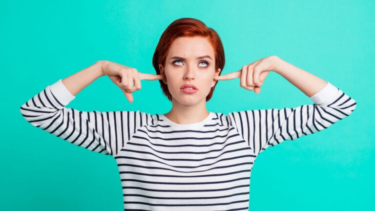 Portrait of nice pretty charming attractive sad red-haired lady wearing striped pullover rolling eyes up closing ears with forefingers isolated over bright vivid shine green turquoise background.
