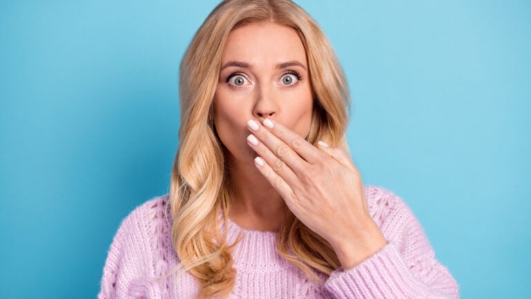 Photo portrait of blonde woman wearing pink pullover amazed shut mouth with hand staring isolated on bright blue color background.