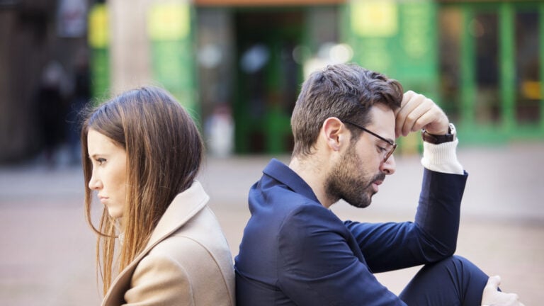 Bad relationship concept. Man and woman in disagreement. Young couple after quarrel sitting back to back. Outdoor.