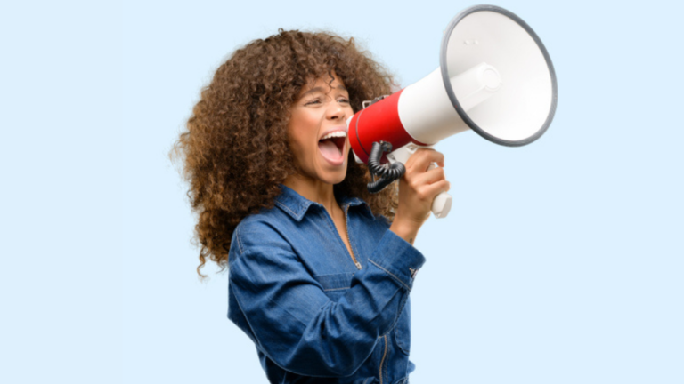 African american woman wearing blue jumpsuit communicates shouting loud holding a megaphone, .