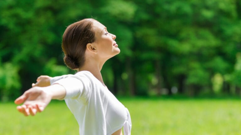Profile of woman with outstretched arms and eyes closed. Concept of healthy lifestyle and relaxation.
