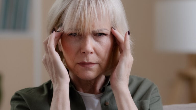 Caucasian ill woman feel pain suffer fatigued dizzy frustrated migraine symptom senior middle-aged lady touch head feeling headache pressure at home.