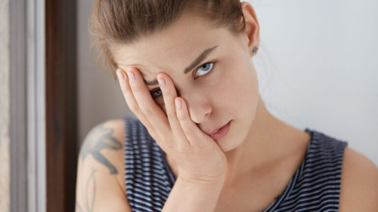 Beautiful portrait of bored female resting half of her face on her palm.