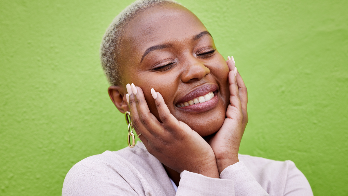 Laughing, black woman and self love or pride on a green wall for fashion, thinking or trendy. Smile, young and a calm African girl or fun model with confidence, fashion or peace on a background treat yourself on a budget.