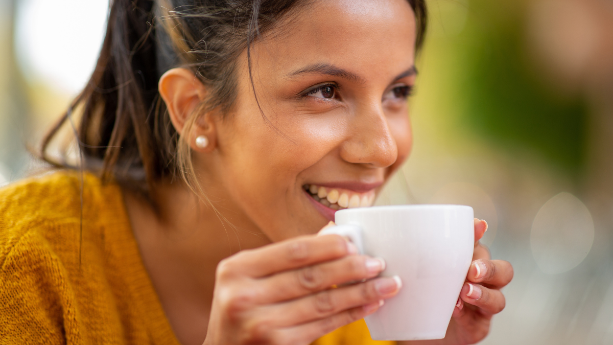 Close up portrait smiling young woman drinking cup of coffee.