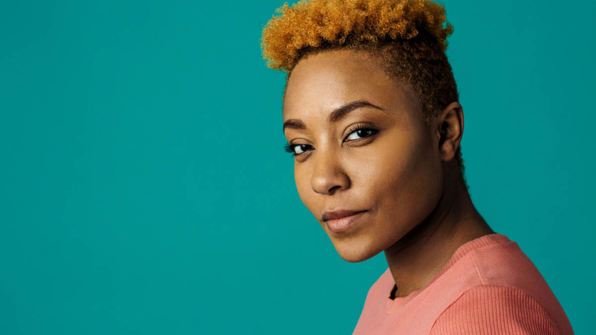 Portrait of a serious young african female with cool short hair looking at camera, against studio background