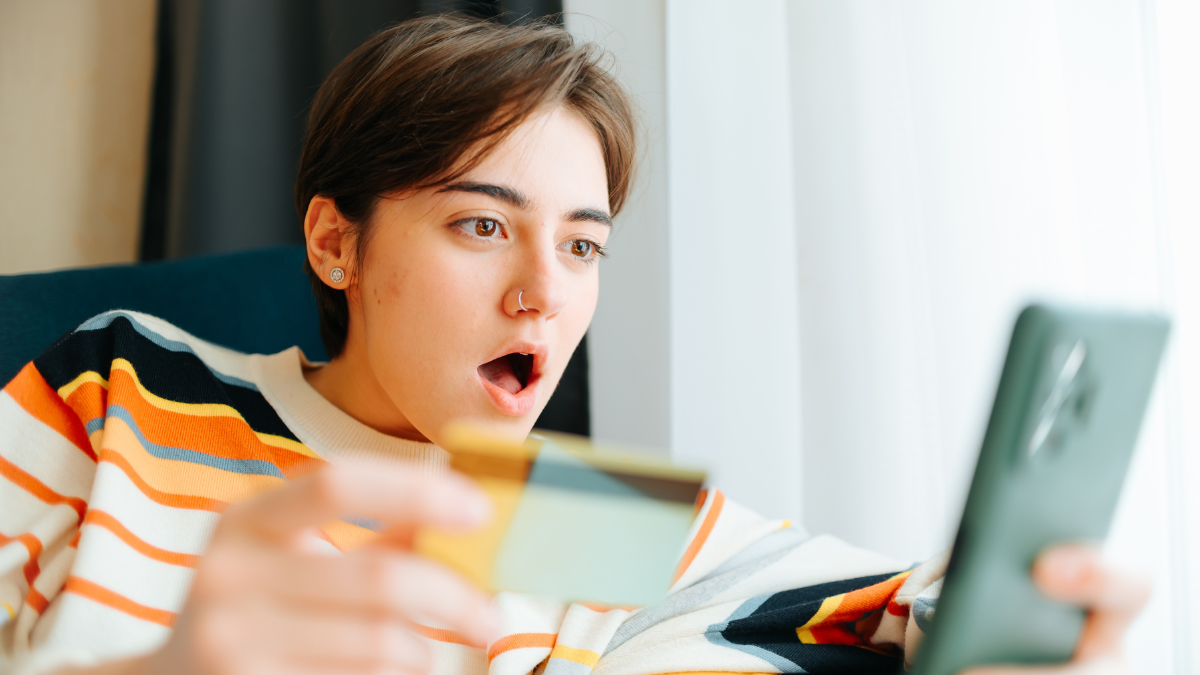 A young person sits on a chair, engaged with their smartphone while holding a credit card, showing an expression of surprise. Pieces of Advice That Sounds Useless Until You Try It SH
