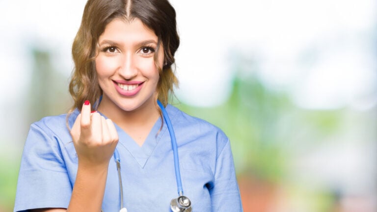Young adult doctor woman wearing medical uniform Beckoning come here gesture with hand inviting happy and smiling.