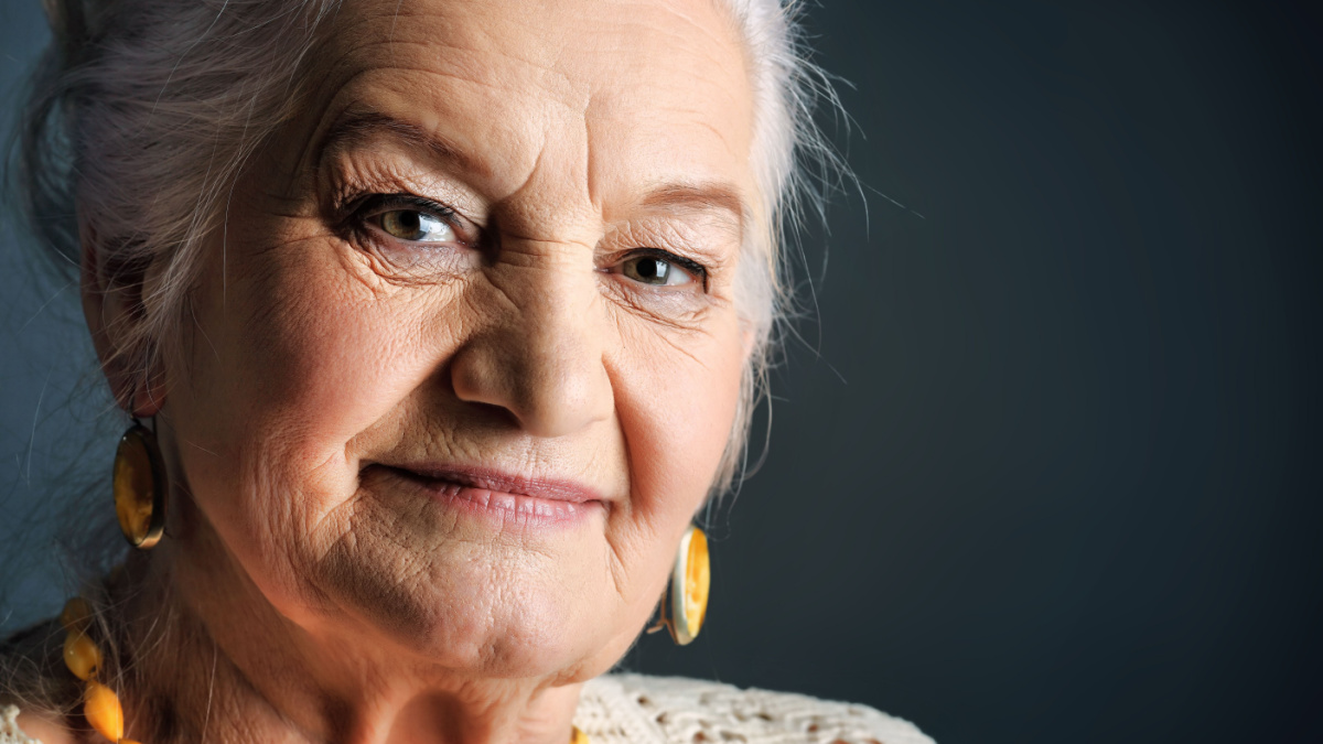 Portrait of a smiling senior woman. Studio shot over grey background.