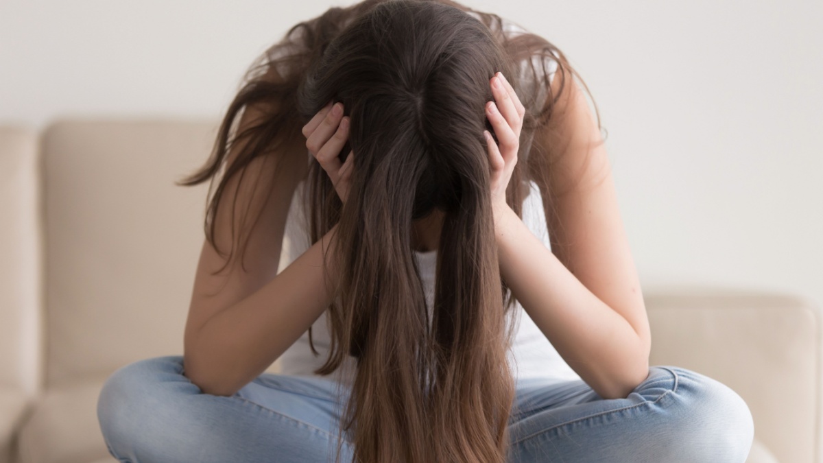 Depressed teenager sitting holding head in hands, Why do I feel guilty about spending money?