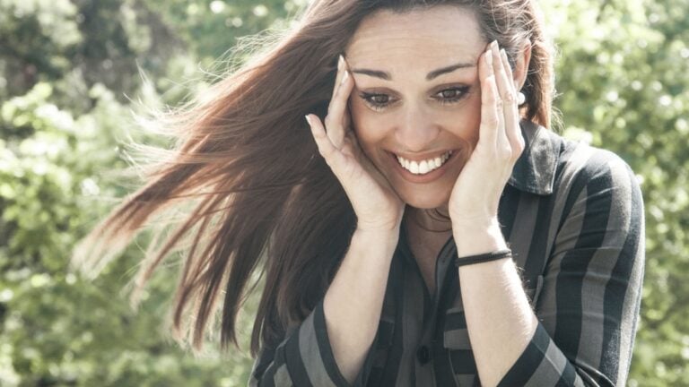 Happy overjoyed girl seeing something cute or getting good news. Surprised shocked woman in casual touching head, smiling and looking down.