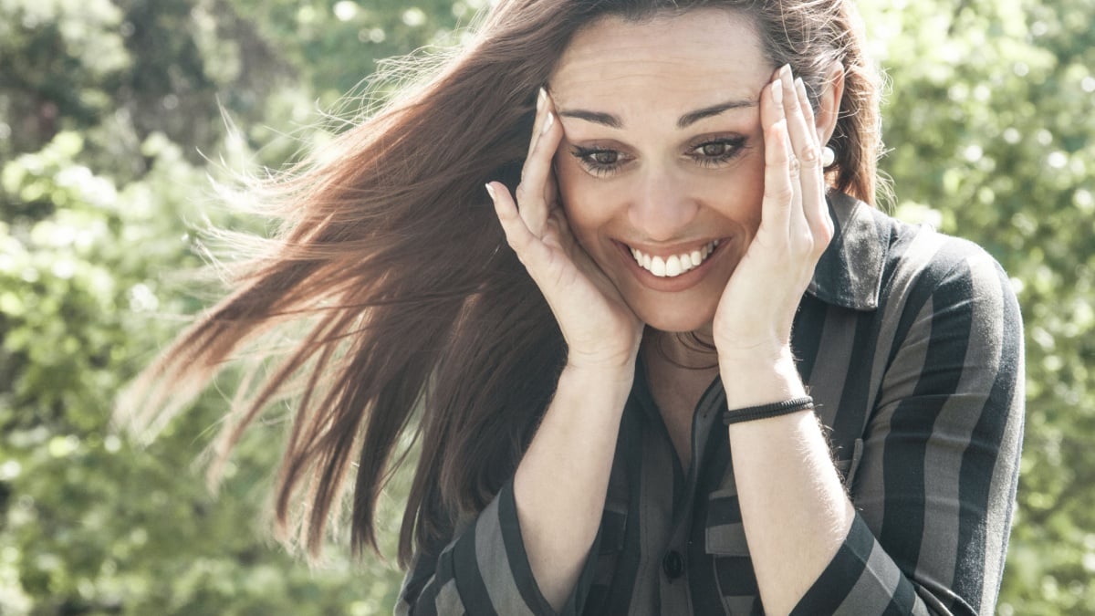 Happy overjoyed girl seeing something cute or getting good news. Surprised shocked woman in casual touching head, smiling and looking down.