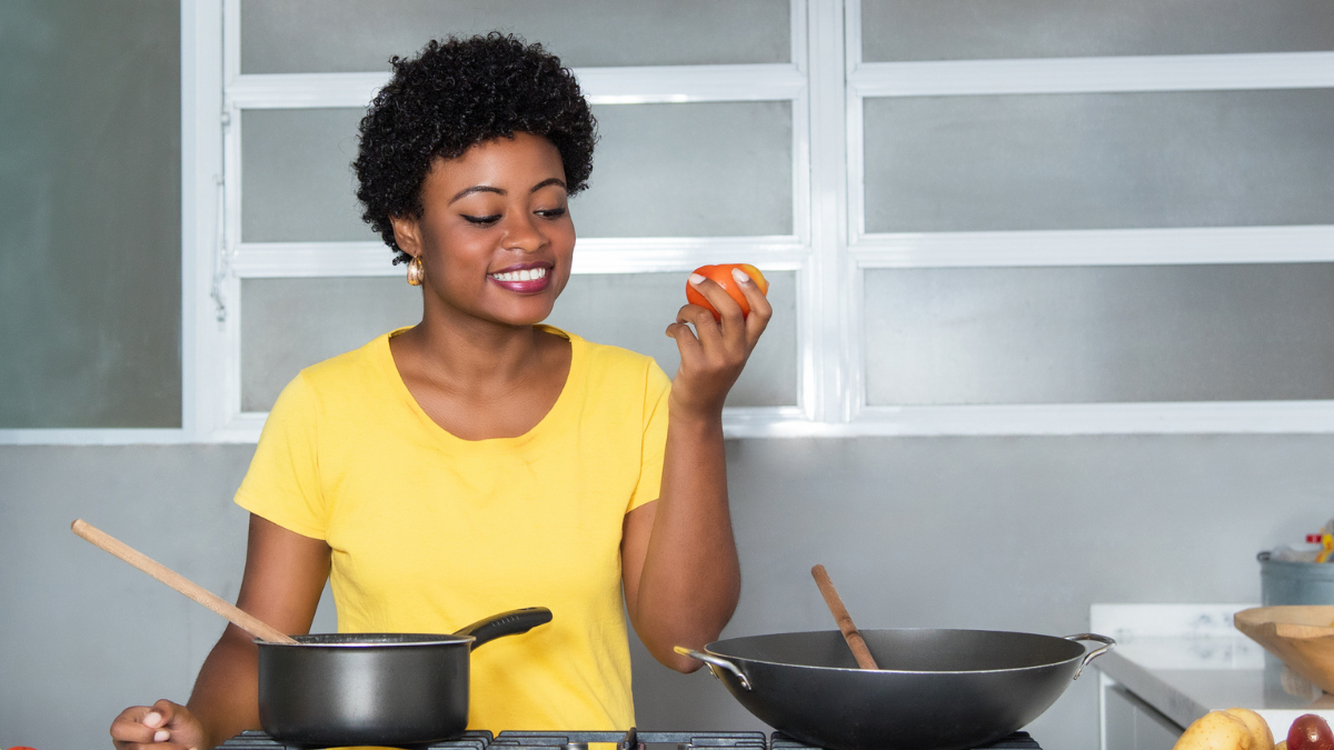 African american woman cooking with tomato at kitchen.