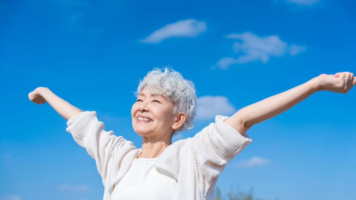 Senior woman taking a deep breath outside.
