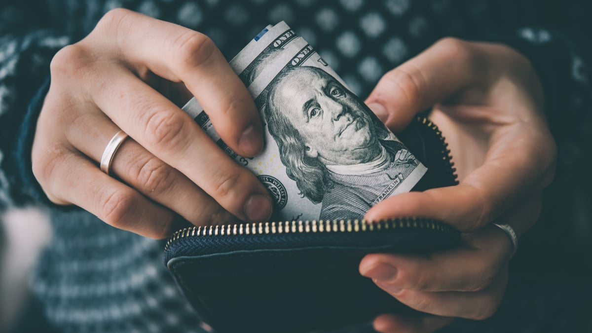 Hands holding us dollar bills and small money pouch. Toned picture.
