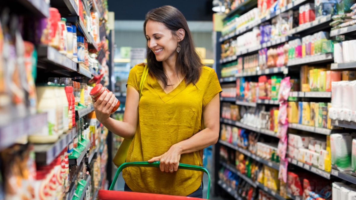 Happy mature woman looking at product at grocery store.