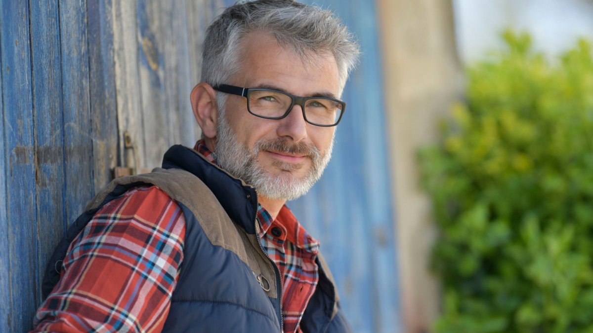 Portrait of farmer leaning on cowshed door.