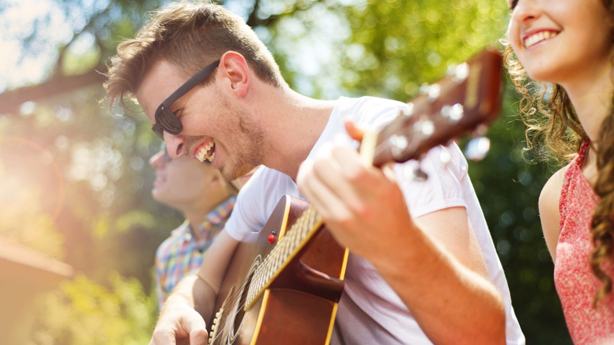 Group of happy friends with guitar having fun outdoor.