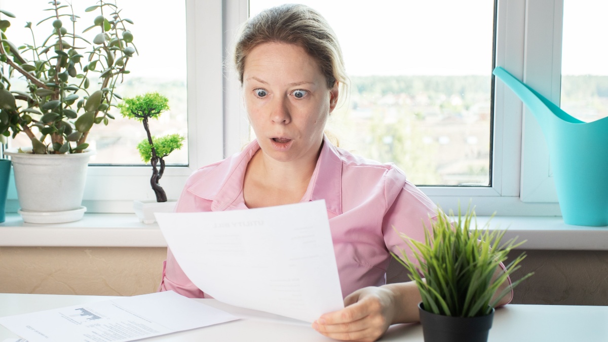 woman surprised by utility bills, Shocked woman looking at letter, reviewing papers with bank documents.
