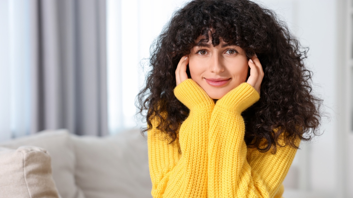 Young woman in stylish yellow sweater indoors.